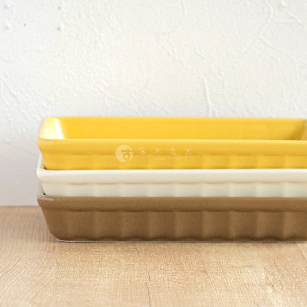 疊放的三個美濃燒釉彩萬用長方烤盤，分別為亮黃、米白與棕色。烤盤為陶瓷材質，具有方正的長條形狀，側面帶有垂直的壓紋設計。