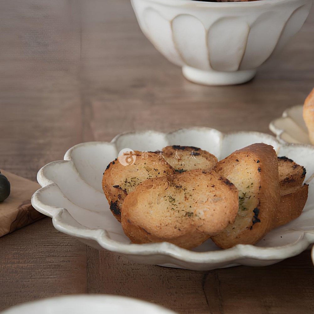 六魯粉引花型主食盤，盤面呈現花瓣狀，邊緣帶有自然的釉色變化，盤中盛有烤製的蒜香麵包丁。