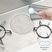 廚房瓦斯爐上，一個圓形淺灰色矽膠水槽蓋，中央有十字紋路，旁邊是爐架和一隻手正用量勺舀取白色粉末。