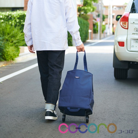 一位男士正拖著一個深藍色的可折疊購物車，購物車有兩個輪子和兩個提把，購物車上有品牌標誌。