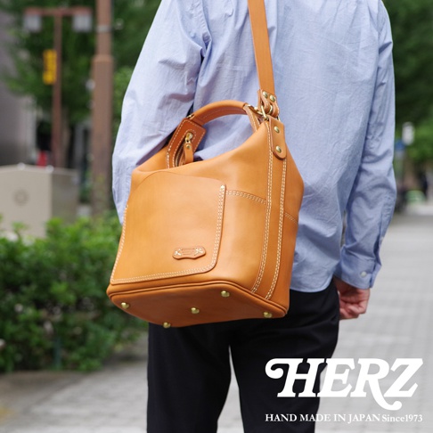 職人手作皮革厚實單肩波士頓包，採用淺棕色皮革，搭配白色縫線及金色五金配件，包款設計簡潔，容量充足。