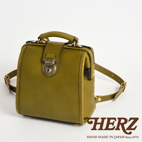 橄欖綠皮革迷你後背醫生包，具有經典醫生包造型，附有金屬旋轉鎖扣和提把，肩帶為皮革材質。