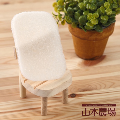 白色蒟蒻QQ薄型海綿，質地細緻，置於木質展示架上，背景有綠植盆栽。