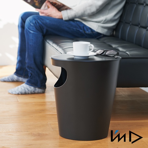 黑色圓筒形儲物垃圾桶置物邊桌，帶有側面開口，桌面擺放著白色咖啡杯、碟子和一副眼鏡。