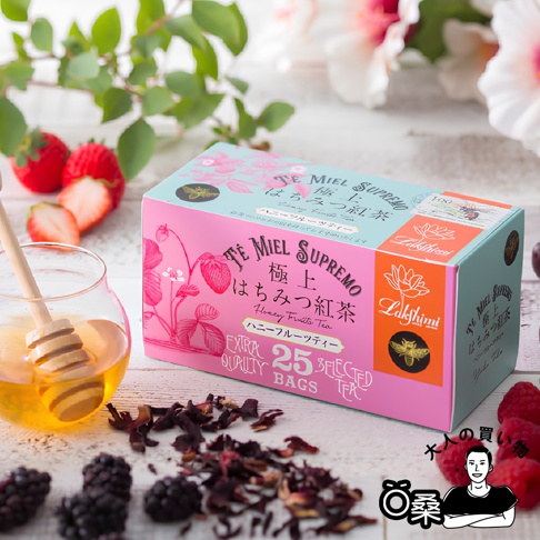 箱裝 Lakshimi 蜂蜜風味水果紅茶，包裝上有草莓圖案，旁邊放有蜂蜜罐、茶葉和各式莓果。