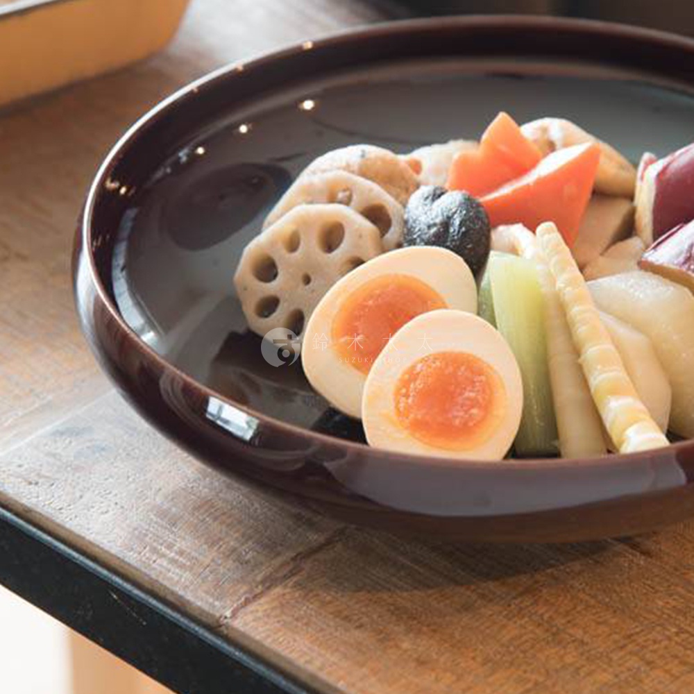 赤飴釉美濃燒圓盤盛有日式關東煮，包括半顆溏心蛋、蓮藕片、紅蘿蔔塊、竹筍和芋頭。