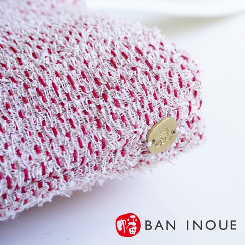 BAN INOUE 蚊帳棉裂織手提袋，淺色棉麻織物上交織著鮮豔的紅色線條，右側有圓形金色品牌標籤。