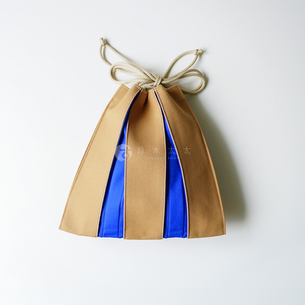 這是一個設計獨特的京都KOSHO ougi帆布信玄袋，外觀呈現扇形摺疊結構。袋身以淺棕色帆布與亮藍色布料交錯拼接，頂部配有同色系繩結作為束口，整體造型簡約且具日式風格，展現出具立體感的摺扇意象。