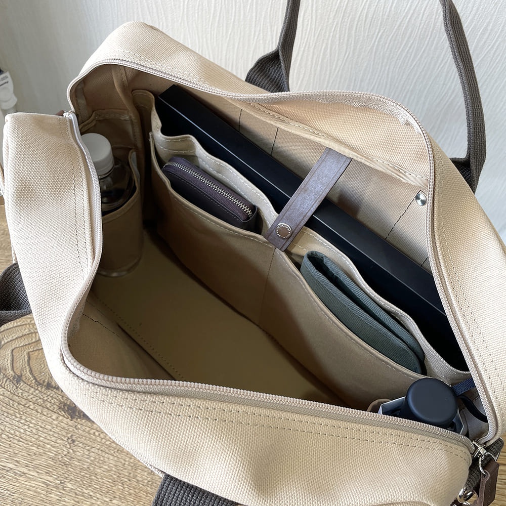 淺卡其色純棉帆布商務公事包，內有隔層，可放入筆記型電腦、錢包、水瓶和雨傘。