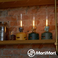 三盞LED煤油燈藍牙音響，分別為黃色、墨綠色和淺綠色，均帶有透明玻璃燈罩和金屬細節，置於木架上。