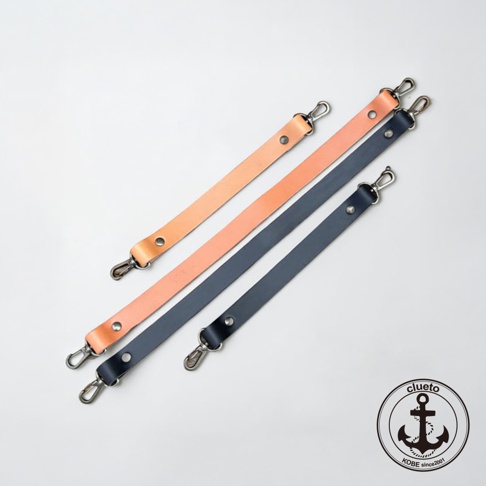 白色背景上展示了四條神戶clueto品牌的皮革短手提帶，分為淺棕色與深藍色兩款，每條帶子兩端均裝有金屬扣環並以鉚釘固定，右下角附有圓形的品牌商標，上面印有 clueto KOBE since 2001 與船錨圖案。