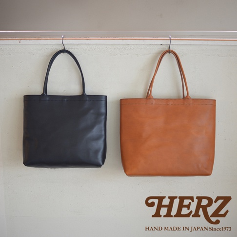 兩個皮革托特包，一個黑色，一個棕褐色，懸掛在牆上。