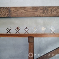 六個透明立方體置物架，每個架子由兩根木頭交叉支撐，內部封存著不同的乾燥植物或物品，如骰子、松果、漿果、種子等，擺放在木質層架上。