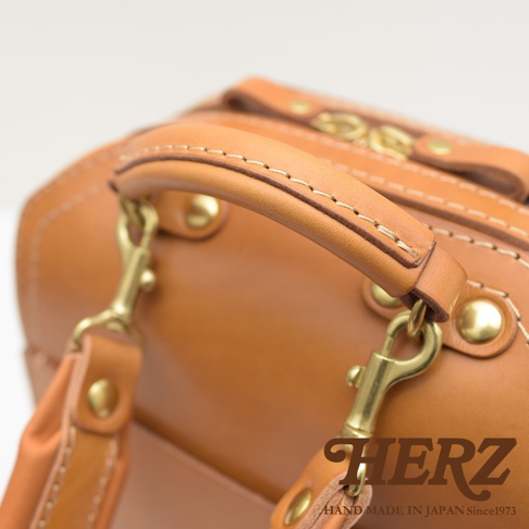 職人手作皮革立體商務後背包 R-3，採用自然棕色皮革，搭配黃銅色金屬扣環與鉚釘，展現精緻工藝與耐用質感。
