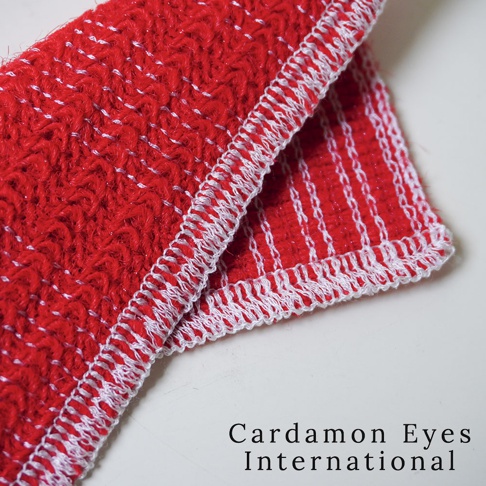 一塊鮮紅色的壓克力纖維清潔巾，帶有白色縫邊，表面織有條紋和鋸齒狀圖案，材質柔軟。