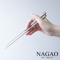 一雙銀色不鏽鋼筷子，由手持，筷子細長，頂端尖銳，整體呈現金屬光澤。