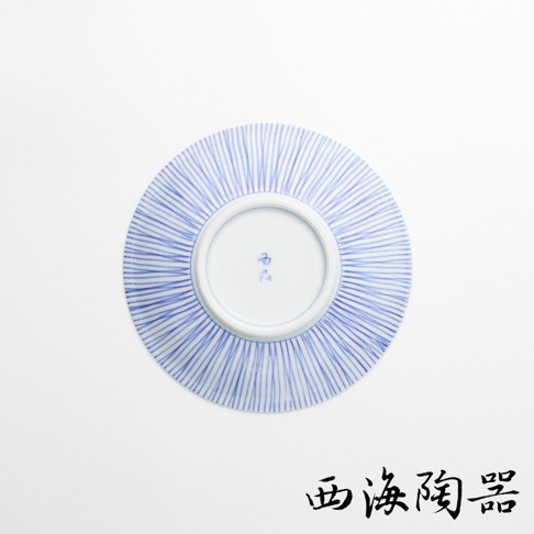 一個白底藍色十草紋的陶瓷點心碟，碟面有放射狀的細長藍色線條，中央的白色圓圈內有藍色書法字樣。