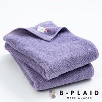 疊放的紫色薄手鱗紋浴巾，表面有細緻的織紋，其中一條浴巾的角落處可見白色品牌標籤，標籤上有「B-PLAID」字樣及公司Logo。