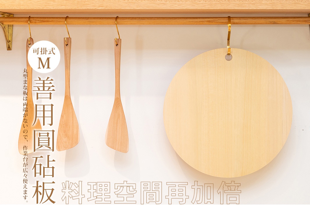 掛式圓形木質砧板，淺木色，表面光滑，邊緣圓潤，頂部有掛孔，旁邊懸掛兩支木製鍋鏟。