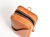 職人手作皮革兩用直立型斜背包，呈現自然棕色皮革，包身方形，頂部有黃銅色拉鍊和 D 型環，側邊有開放式口袋，縫線清晰。