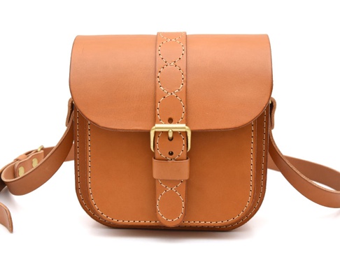 棕褐色皮革單肩包，正面有十字繡紋飾帶和金色搭扣，側面和邊緣有明顯縫線。