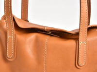 職人手作皮革直式肩背托特包，以淺棕色牛皮製成，設有對比色的縫線和皮革提把。