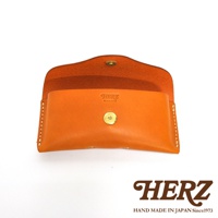 橙色皮革製成的眼鏡收納盒，盒蓋處有HERZ字樣烙印，並有金色金屬釦，盒身縫線精緻，下方另有HERZ品牌標誌。