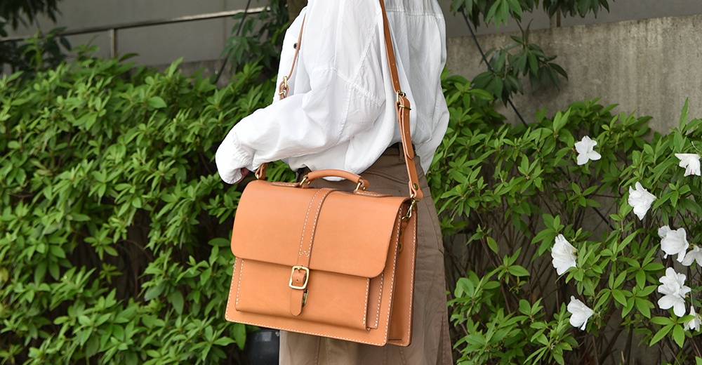 淺棕色皮革三用單扣商務後背包，有頂部提把、可調式斜背帶，側面及縫線細節清晰可見。