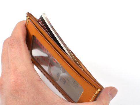 手持式橫式票券收納夾，採用棕色皮革製作，配有透明卡片視窗，內含多張卡片。