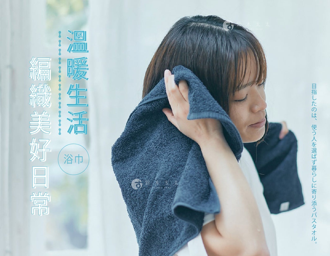 一位女子正用深藍色毛圈織物浴巾擦拭頭髮。浴巾質地細緻，呈現緞澤光澤。