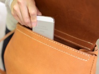 職人手作皮革屋瓦風迷你後背包，採用天然皮革材質，呈現溫潤的焦糖棕色。包身縫線清晰，內部空間可放入手機。