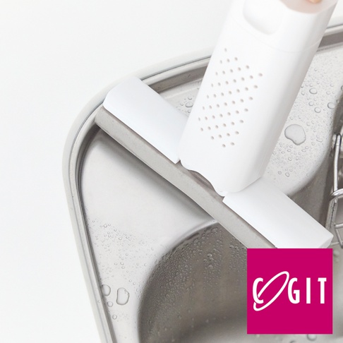 白色推拉式海綿清潔刷，帶有多孔設計，置於不鏽鋼水槽邊緣，水槽表面有水珠。