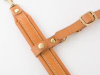 職人手作皮革背包用減壓胸前扣帶 (KO-2)，以淺棕色皮革製成，搭配黃銅色金屬扣件和鉚釘，縫線整齊，設計簡約。