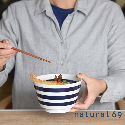 一個 navy blue 和白色條紋的丼碗，裝有天婦羅和蔥花，由一位人士手持，並用木筷子夾起食物。