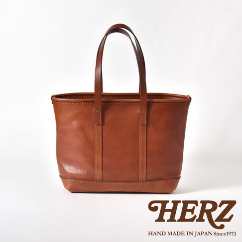 一個棕褐色的皮革托特包，帶有兩個皮革提把，包包正面有縫線裝飾。