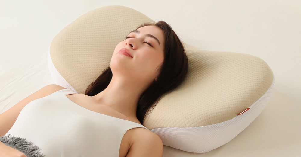一名女子仰臥在一個符合人體工學的淺黃色枕頭上，閉著眼睛，面帶微笑。