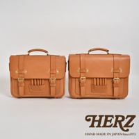 兩個棕褐色皮革製成的傳統歐風三用學生包，一前一後並排展示，皆有翻蓋、金屬釦環、提把及雙肩帶。