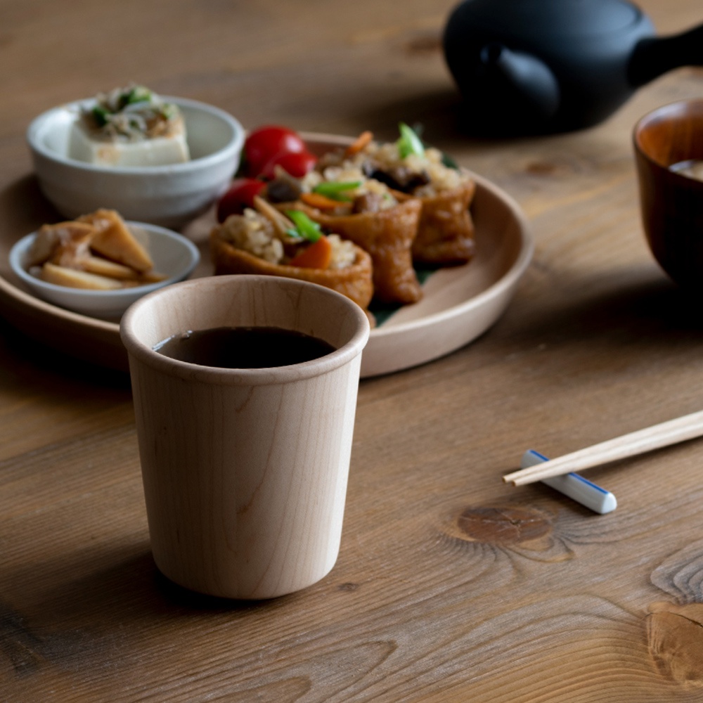 淺色楓木製寬口杯，盛有深色液體，杯身呈現自然木紋。