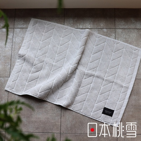 淺灰色毛巾浴墊，表面有菱形紋理，材質柔軟。