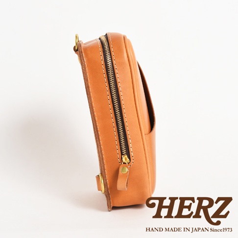 日本HERZ職人手作皮革兩用直立型斜背包，以棕色皮革製成，從側邊拍攝，展示了其拉鍊及品牌標誌