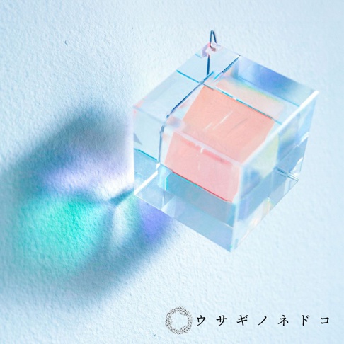 透明的稜鏡立方塊吊飾，內部嵌有粉色方塊，透過光線折射出彩虹光暈。