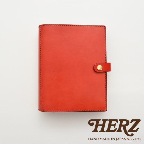 職人手作皮革A5手帳/記事本書套，鮮豔紅色皮革，附有金色銅扣，邊緣縫線整齊，展現精緻工藝。