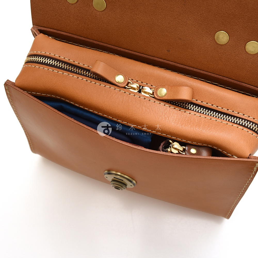 模式B： 日本HERZ 職人手作皮革多功能收納單肩包 Q-9 棕色，打開的包內有拉鍊隔層，可見印有SUZUKI SHOP字樣的標籤。