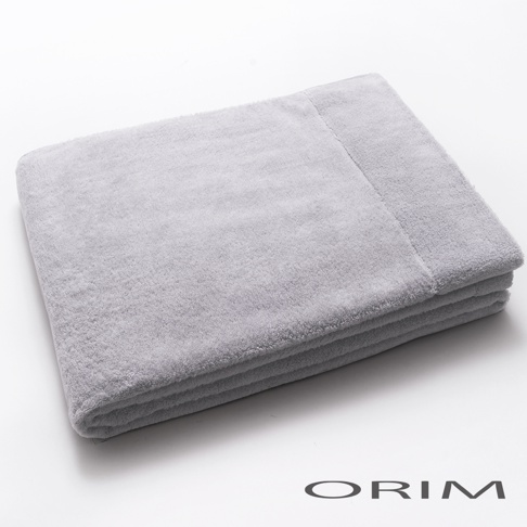 一張摺疊的淺灰色毛巾，材質輕柔，表面有細緻的絨毛感，毛巾邊緣有明顯的縫線，整體呈現簡潔的設計。