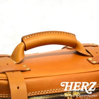 職人手作皮革大型三用旅行後背包 A-21，特寫展示包款的頂部提把及部分箱身，以質感棕色皮革製成，細緻車縫線與金屬銅釦點綴，展現精湛工藝。