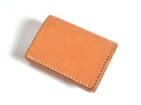 職人手作皮革三折式迷你短夾，呈現原色皮革質感，線條簡潔，以白色縫線勾勒邊緣。