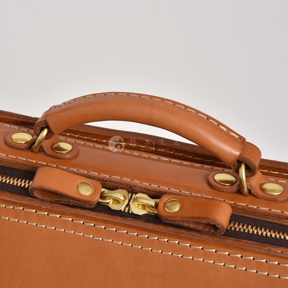職人手作皮革商務電腦後背包 R-25，棕褐色皮革材質，配有金色拉鍊、金屬扣飾及皮革提把，整體風格簡約大方。