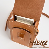 職人手作皮革休閒散步包 CP-52 S，採用淺棕色皮革製成，包身結構紮實，縫線清晰。包蓋開啟，內有筆記本和卡片。包正面有一個小巧的翻蓋口袋，以小皮扣固定。