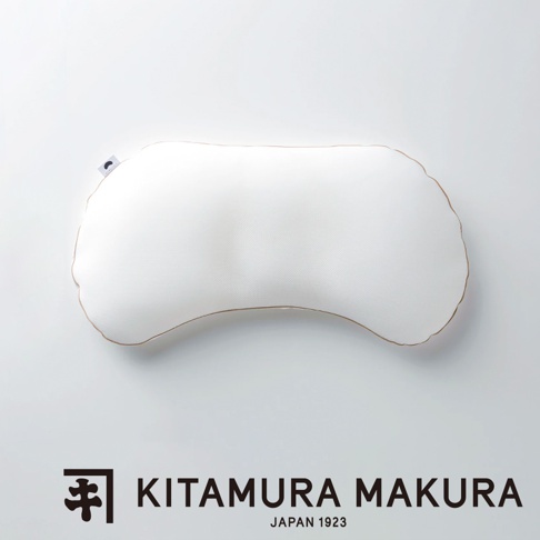 一個白色、彎曲形狀的豌豆枕，邊緣有細緻的縫線，枕頭上印有小小的黑色月亮標誌。