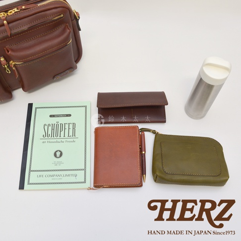 深棕色皮革多功能收納單肩包，搭配淺綠色筆記本、棕色短夾、棕色筆記本與筆、軍綠色零錢包，以及一個銀色保溫瓶。